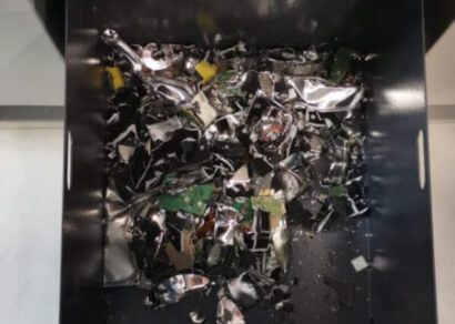 Zerkleinerte Festplatten und IT-Komponenten in einem schwarzen Behälter, demonstrieren professionelle Datenvernichtung und Recyclingprozesse.